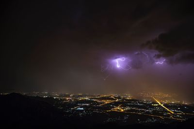 Aerial view of illuminated cityscape against sky at night