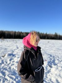 A girl in a pink sweatshirt is standing on the field