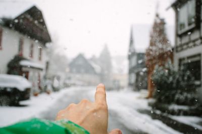 Cropped hand on man pointing on city street during snowfall