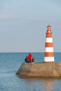 Lighthouse on sea against sky