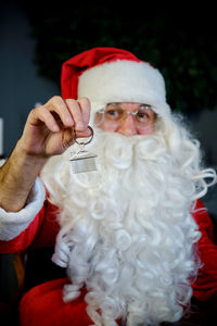 Portrait of man in santa costume holding christmas decoration