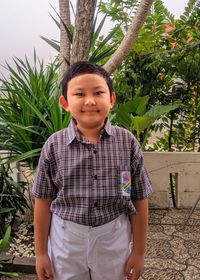 Portrait of boy standing against plants