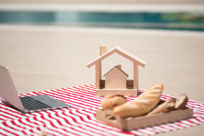 Model home with laptop and bread on beach towel during sunny day