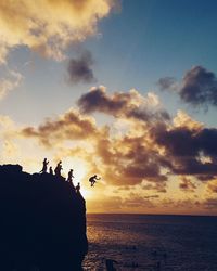 Silhouette people on beach against sky during sunset