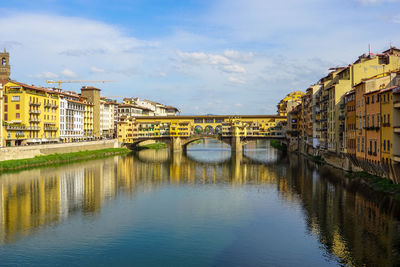 Ponte vecchio over arno river against sky in city