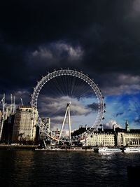 Low angle view of ferris wheel against cloudy sky