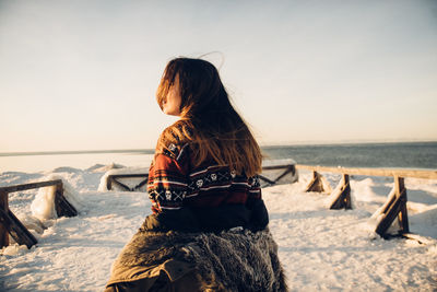 Woman looking at sea against sky during winter
