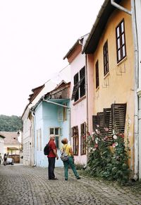 Rear view of people walking on building against sky