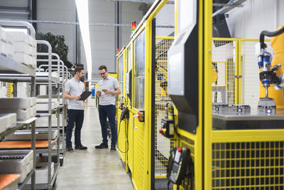 Engineers with file folder having discussion in factory