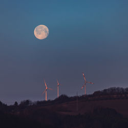 Wind turbines on land against sky at night