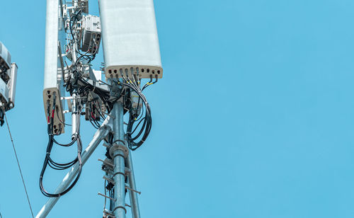 Low angle view of telephone pole against clear blue sky