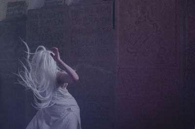 Woman performing against wall in abandoned building