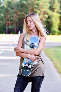 Close-up of woman holding skateboard standing at park