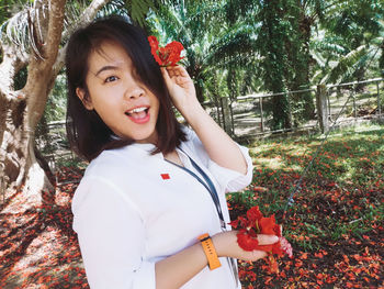 Portrait of smiling woman standing by flowering plants