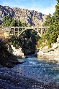 Arch bridge over river against mountains