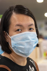 Portrait of woman wearing mask standing indoors