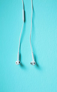 Close-up of in-ear headphones against blue wall