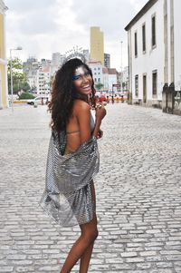 Portrait of smiling young woman standing against building