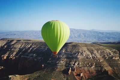 Hot air balloon flying over mountain against sky