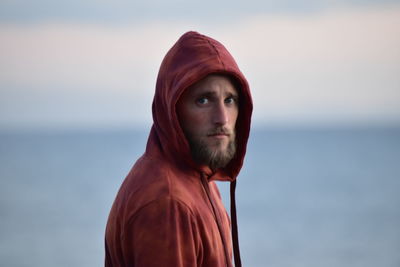 Portrait of young man looking away against sea