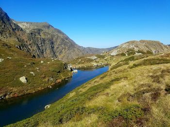 Scenic view of river and mountains against clear blue sky