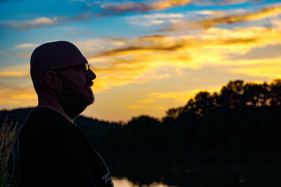 Side view of man standing against sky during sunset
