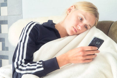 Portrait of teenage girl lying on sofa at home