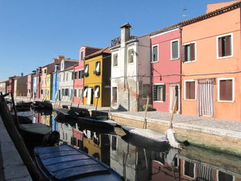 Boats in canal amidst buildings against sky