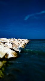 Rocks on sea shore against blue sky