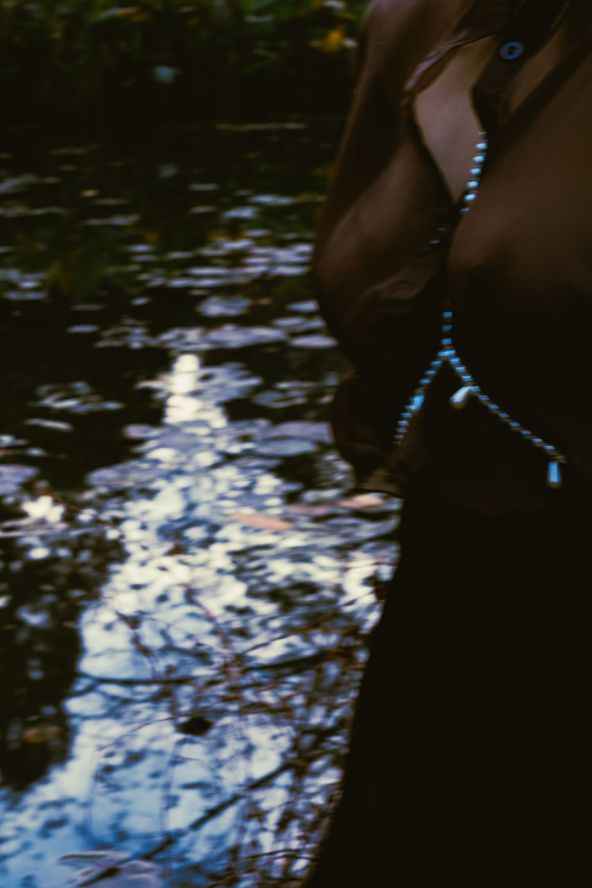 MIDSECTION OF WOMAN STANDING BY WATER