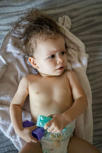 High angle view of cute baby girl lying on bed at home