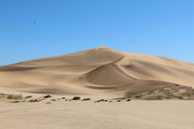 Scenic view of desert against clear blue sky