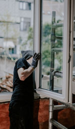 One guy is a builder making repairs by installing a window frame. person