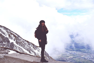 Young woman standing on mountain against sky