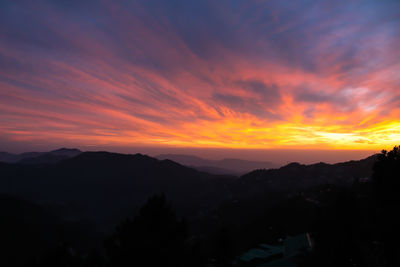 Scenic view of silhouette mountains against orange sky