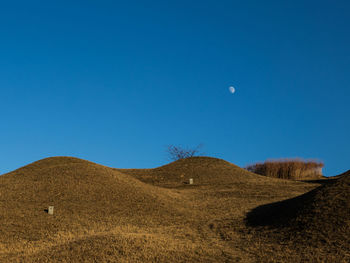 Low angle view of desert against clear blue sky