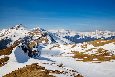 Scenic view of snowcapped mountains against blue sky