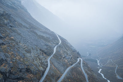 Narrow mountain road on rocky cliffside with mist in background. norway