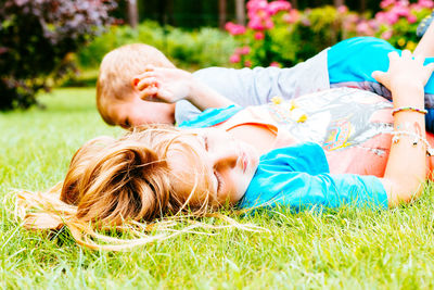 Siblings lying on grassy land