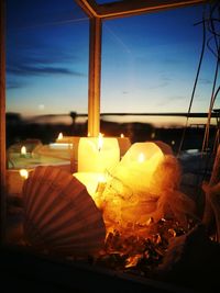 Close-up of lit candles on table against sky at night