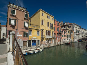 Buildings by canal against clear sky in city