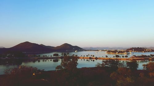 Scenic view of lake and mountains against clear blue sky