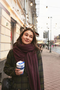 Portrait of smiling young woman standing in city