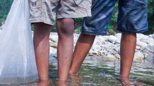 Low section of couple standing by water