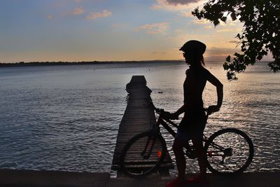 Side view of man standing on bicycle at beach