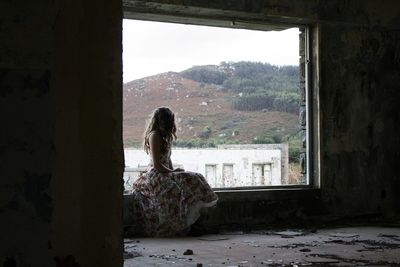 Woman looking at cityscape through window