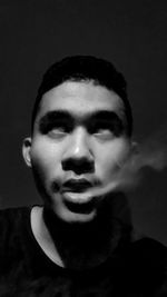 Close-up portrait of young man against black background