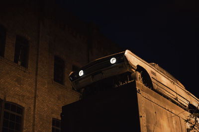 Low angle view of abandoned car against building at night