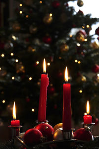 Close-up of burning candles against a christmas tree with christmas decoration