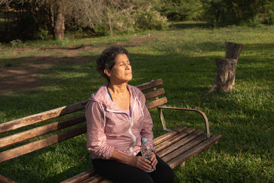 Woman sitting on bench in field